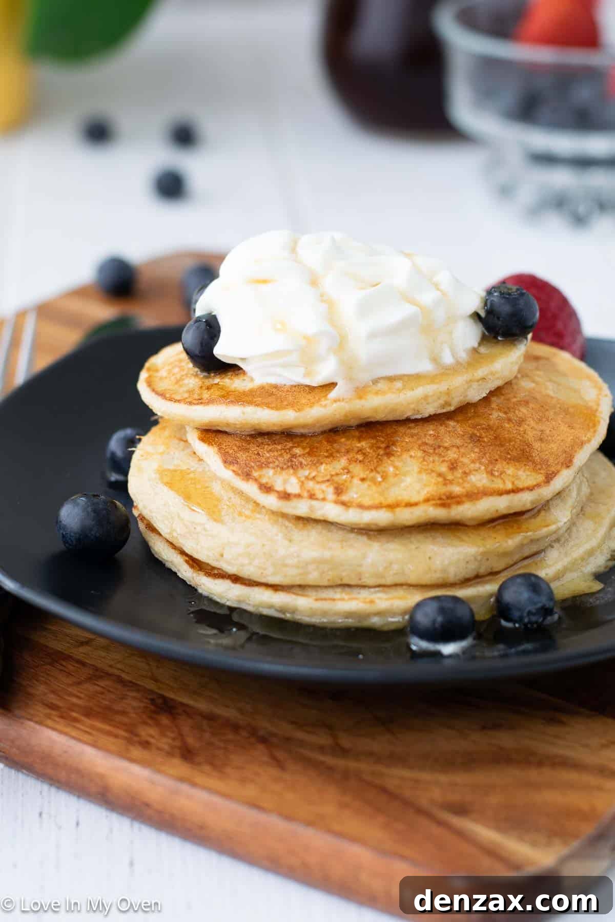 A plate of high protein pancakes topped with peanut butter, Greek yogurt, and fresh berries.