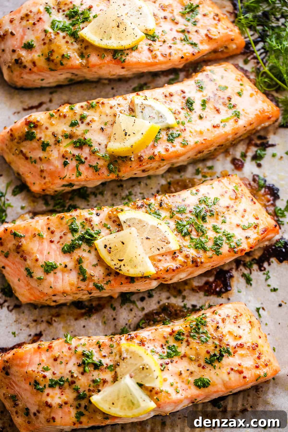 This baked Maple Mustard Salmon recipe is lightly seasoned, then brushed with a sweet and tangy sauce made from maple syrup and Dijon mustard! four baked maple mustard salmon fillets on a baking sheet