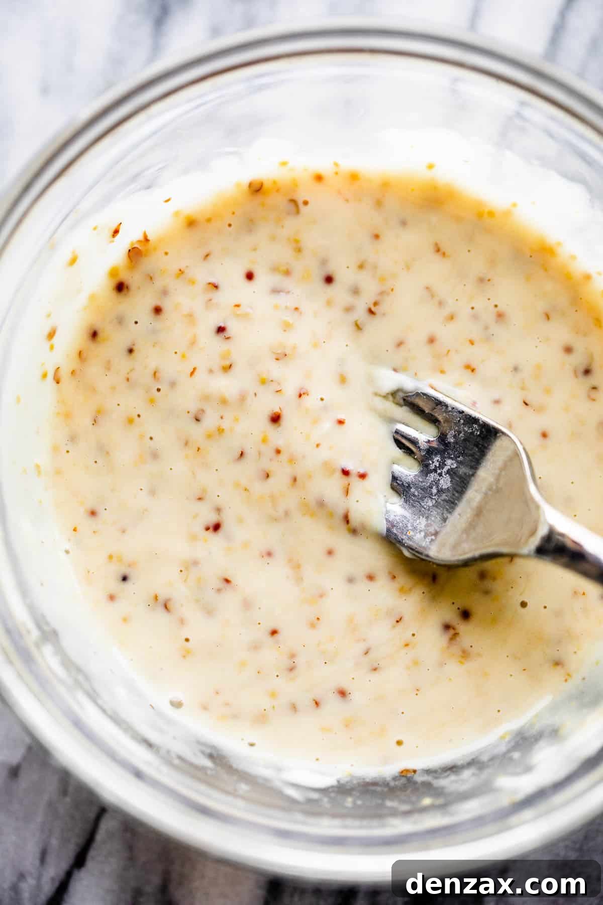 This baked Maple Mustard Salmon recipe is lightly seasoned, then brushed with a sweet and tangy sauce made from maple syrup and Dijon mustard! mixing maple mustard sauce in a glass bowl
