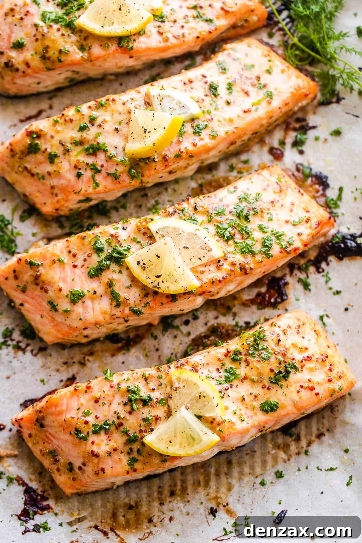 This baked Maple Mustard Salmon recipe is lightly seasoned, then brushed with a sweet and tangy sauce made from maple syrup and Dijon mustard! four maple mustard salmon fillets arranged on a baking sheet