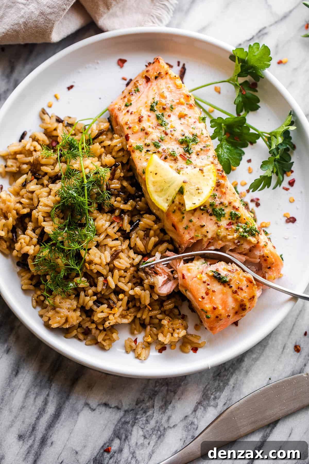 This baked Maple Mustard Salmon recipe is lightly seasoned, then brushed with a sweet and tangy sauce made from maple syrup and Dijon mustard! salmon fillet on white plate served with wild brown rice