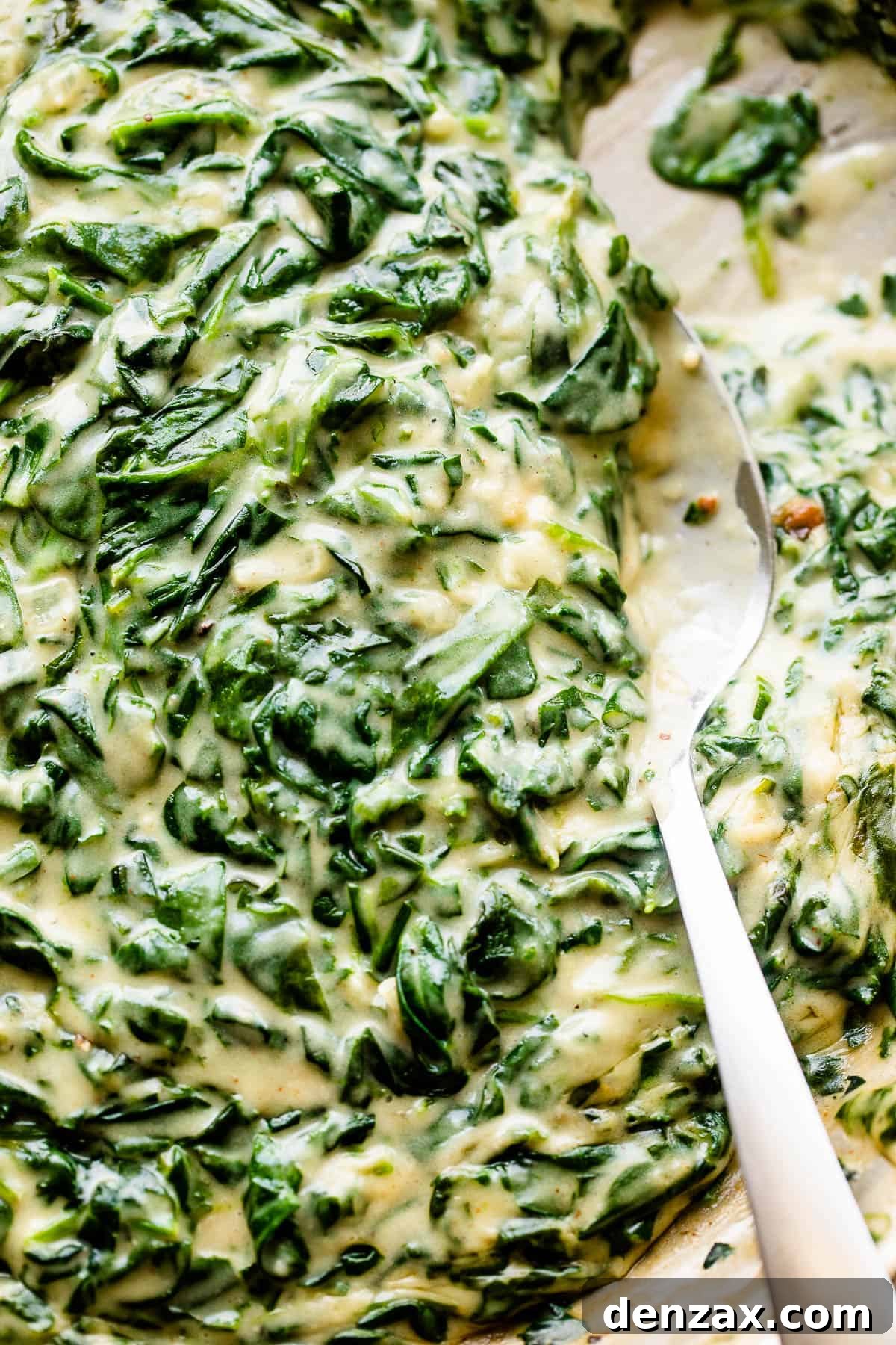 Stirring creamed spinach with a large spoon.