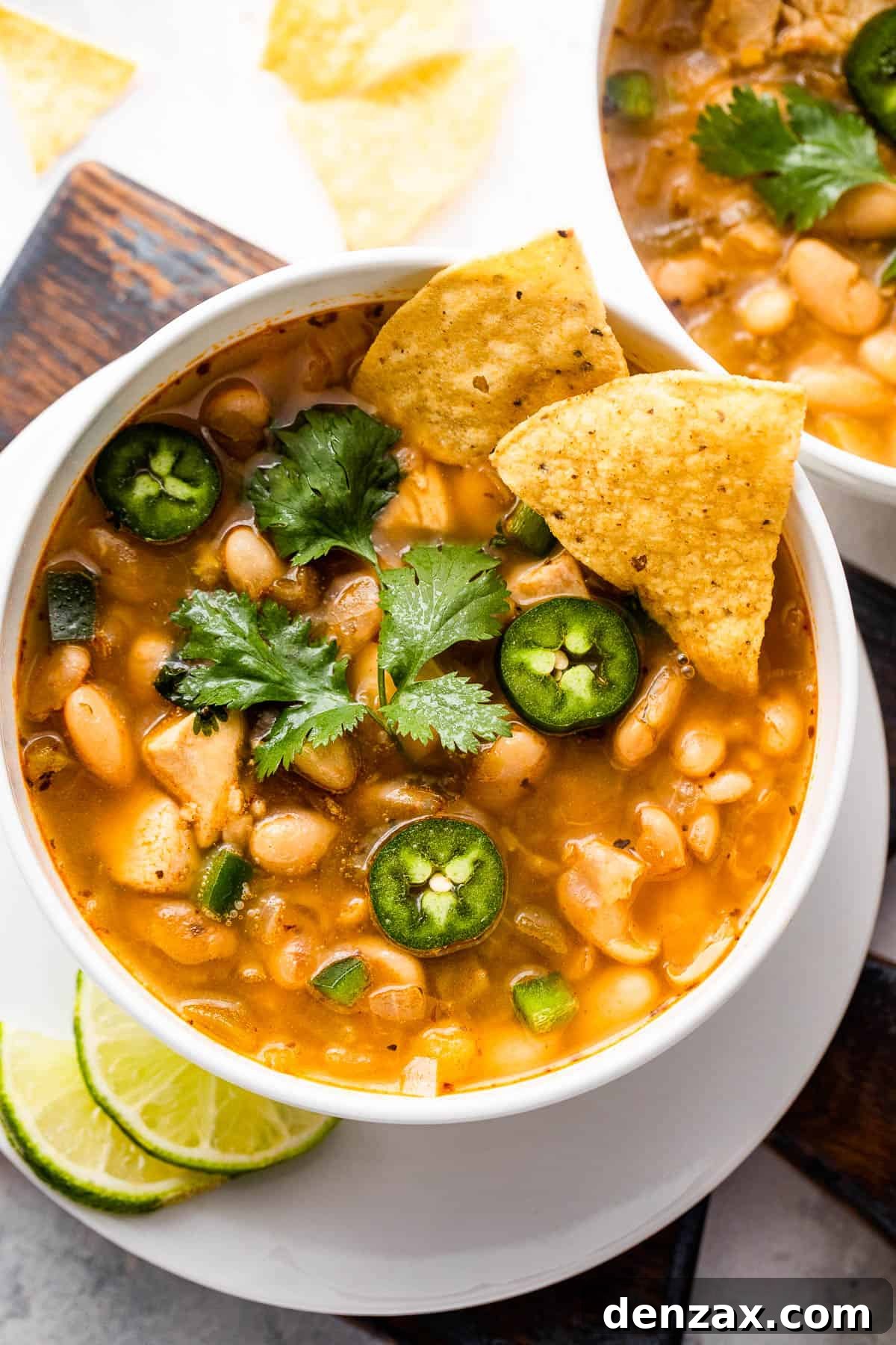 Hearty Chicken Chili 7 overhead shot of white soup bowls with chicken chili, garnished with fresh cilantro and sour cream