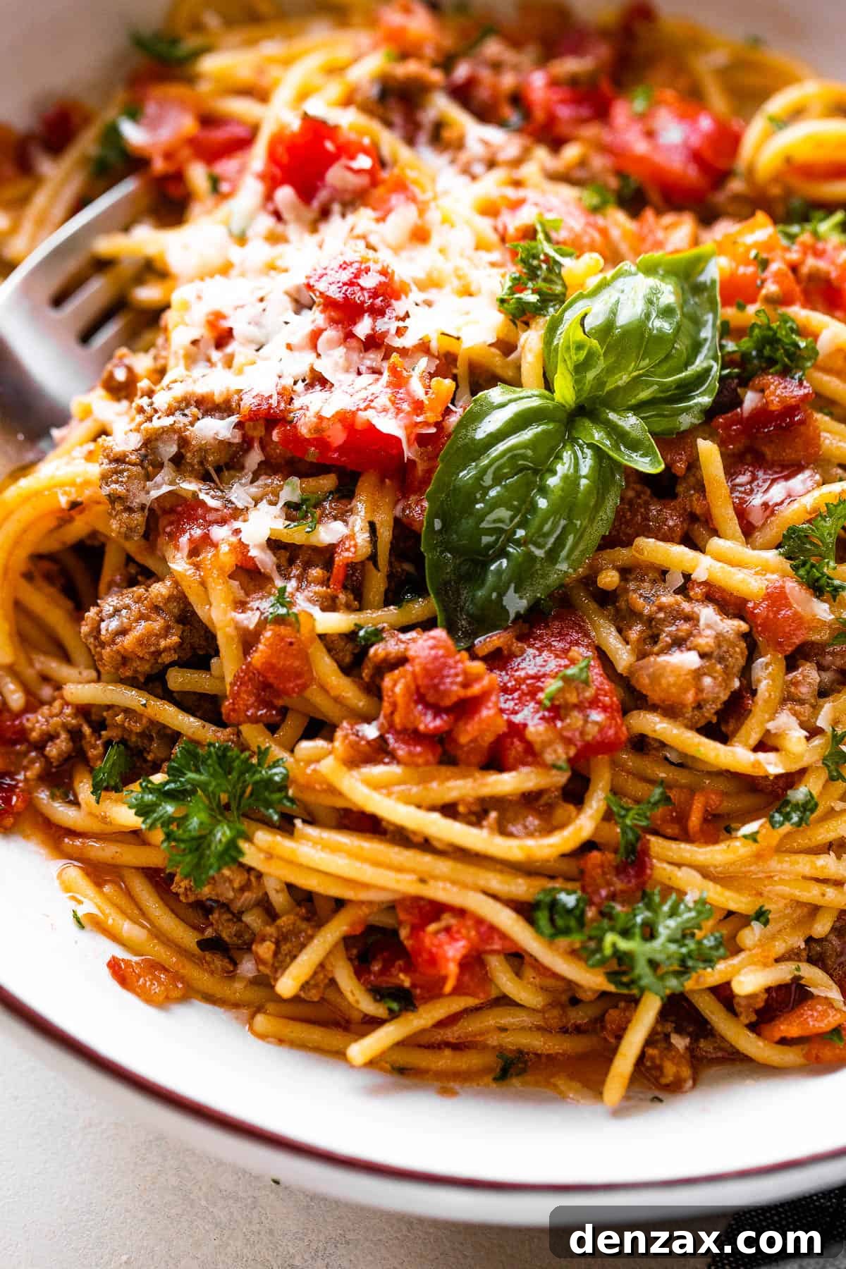 close up shot of spaghetti with ground beef, tomatoes, and fresh basil