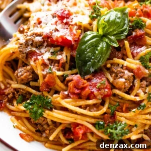 close up shot of spaghetti with ground beef, tomatoes, and fresh basil