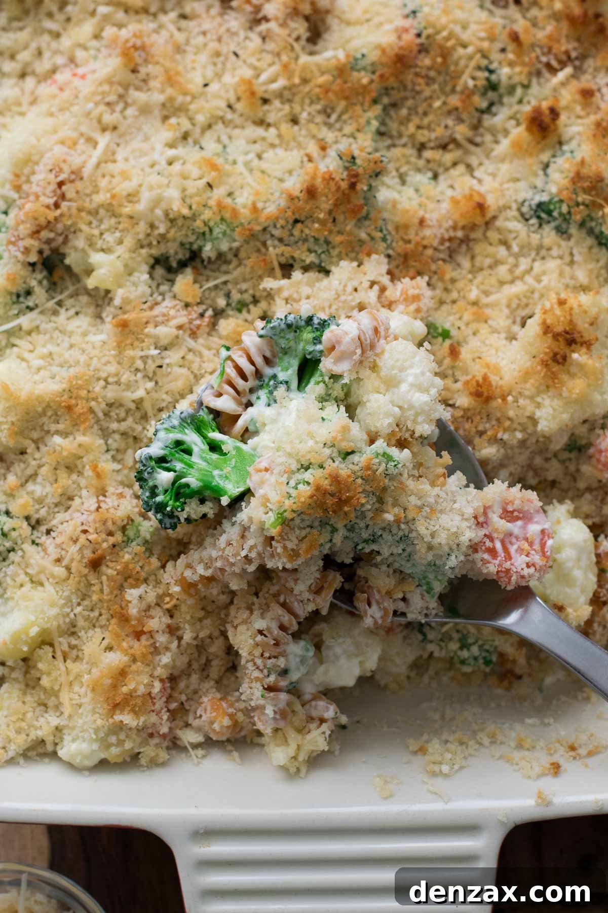 A bowl of uncooked lentil pasta and fresh vegetables (broccoli, cauliflower, carrots, onion) – ingredients for the creamy vegetable casserole.