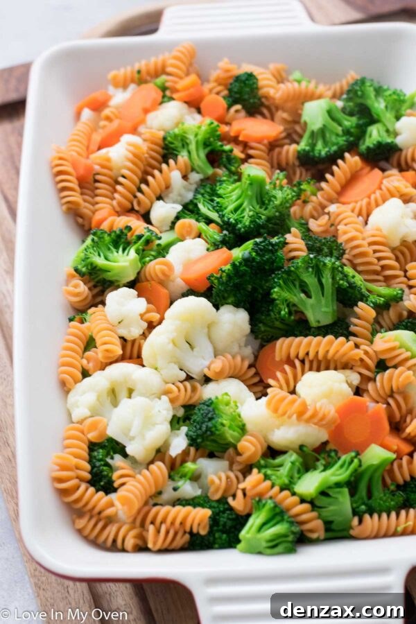 Cooked pasta being drained in a colander, steam rising, ready to be combined with vegetables.