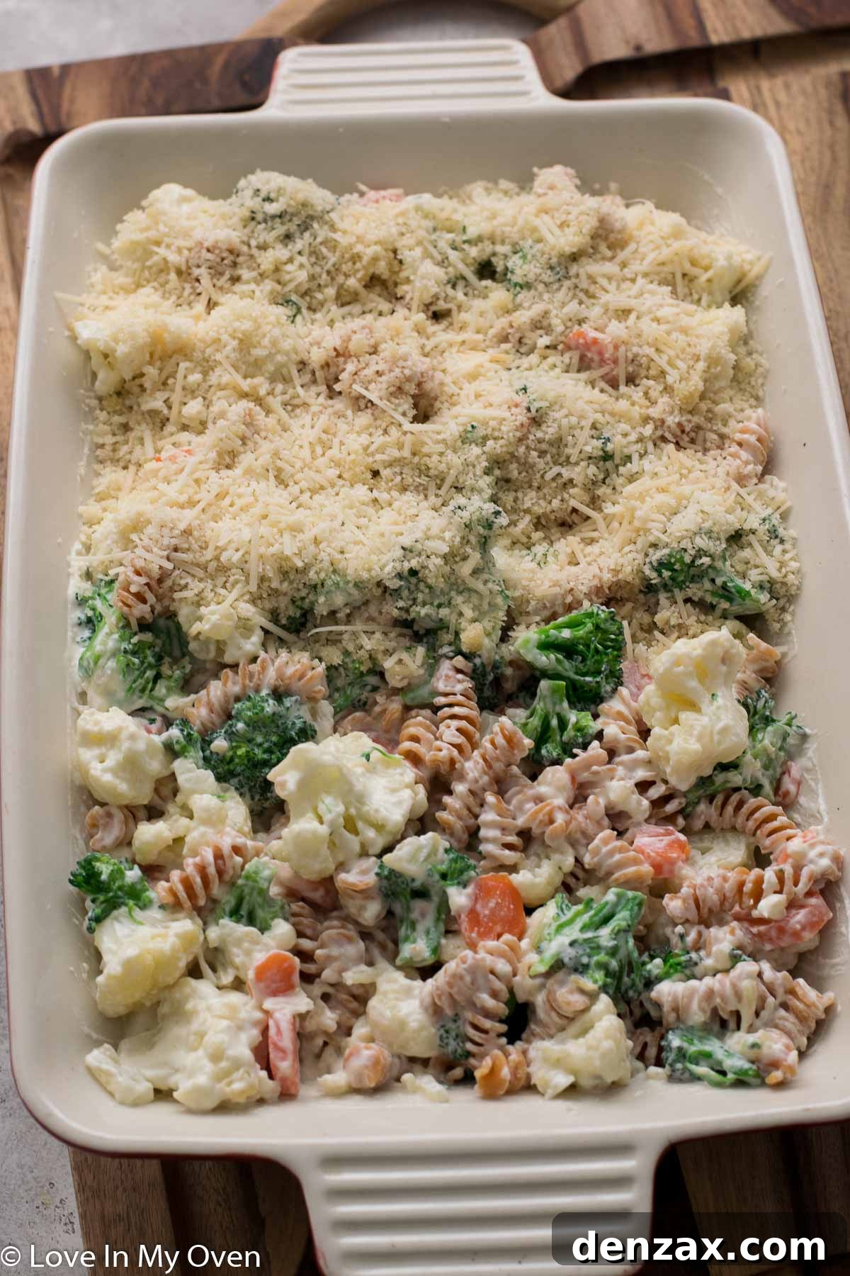 Creamy vegetable casserole in a baking dish, topped with buttery breadcrumbs and cheese, before baking.