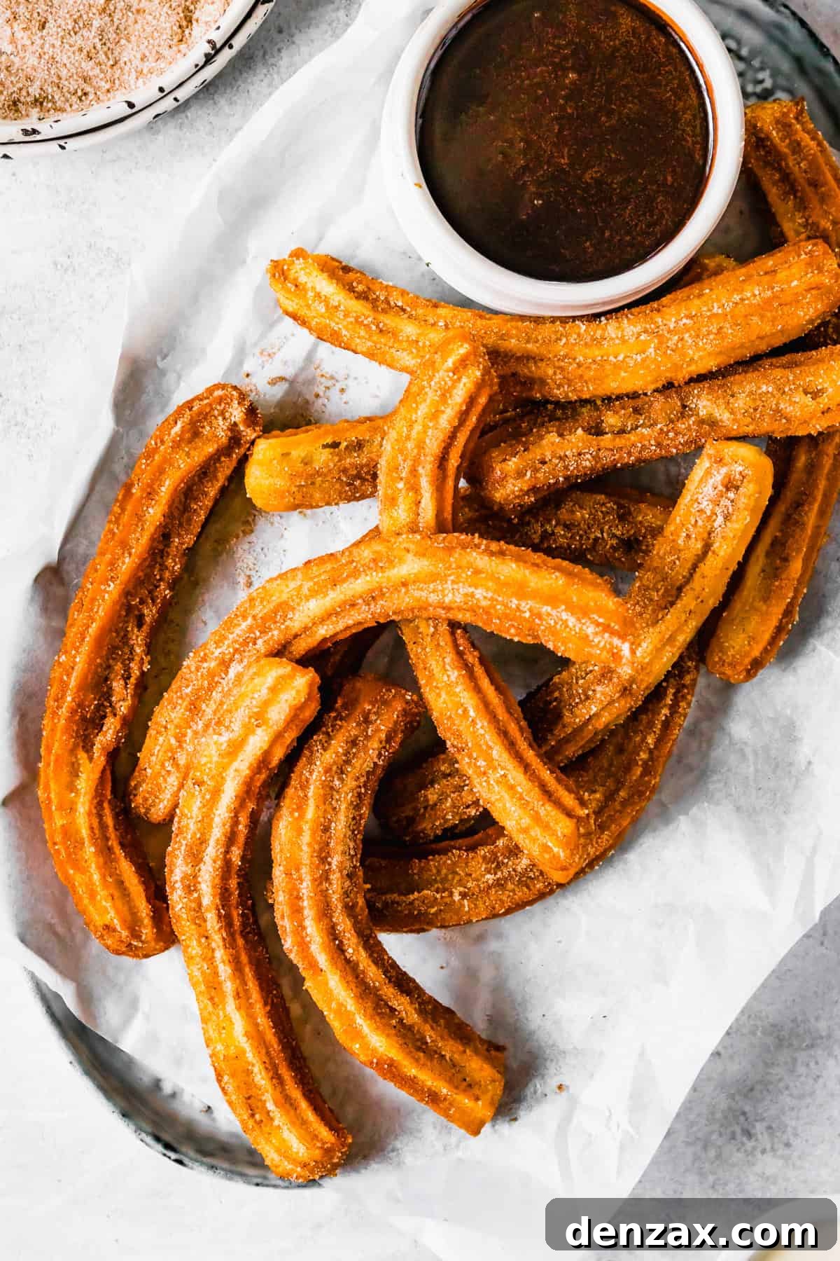 Freshly made churros on a plate, served with a bowl of homemade chocolate dipping sauce. A perfect dessert or snack.