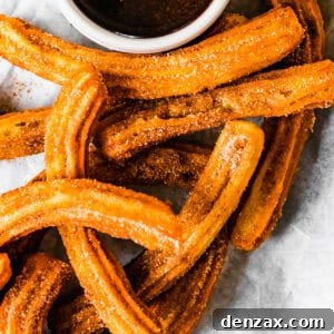 Homemade churros served on a plate with a bowl of chocolate sauce.