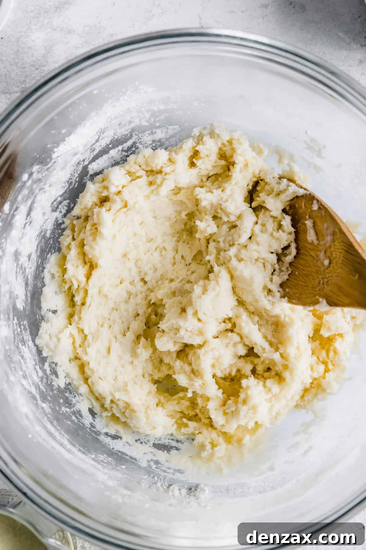 Thick, sticky churro dough resting in a large glass mixing bowl, showcasing its ideal consistency for piping.