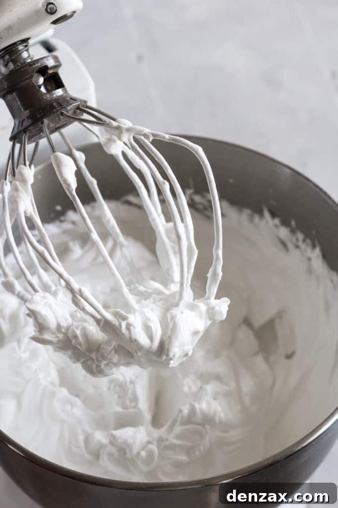 The whisk of a stand mixer with whipped meringue