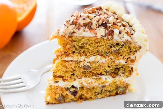 Orange Carrot Cake with creamy white frosting on a wooden serving board.