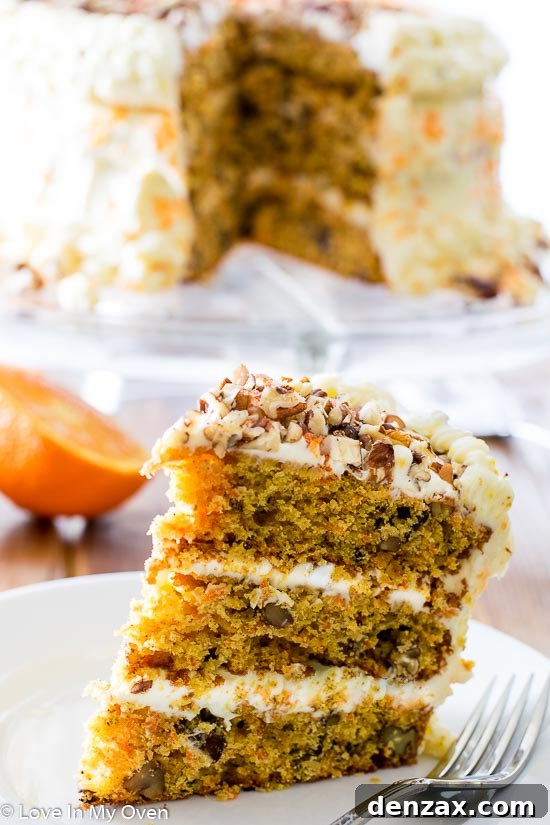 A beautifully frosted Orange Carrot Cake slice on a white plate, ready to enjoy.