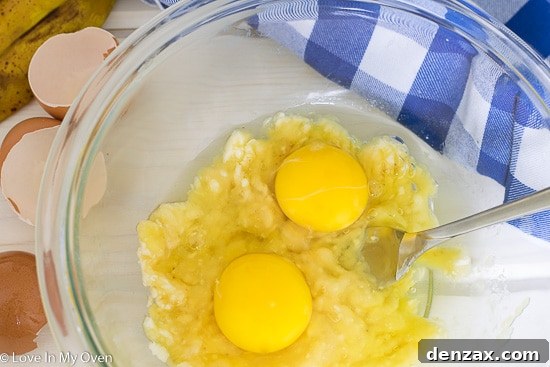 Adding two eggs to mashed banana, preparing the pancake batter