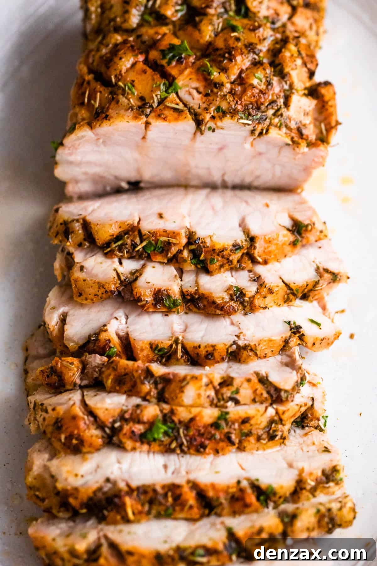 Herb-Crusted Pork Loin and Roasted Root Vegetables 6 overhead shot of cooked and sliced pork roast set on a white background