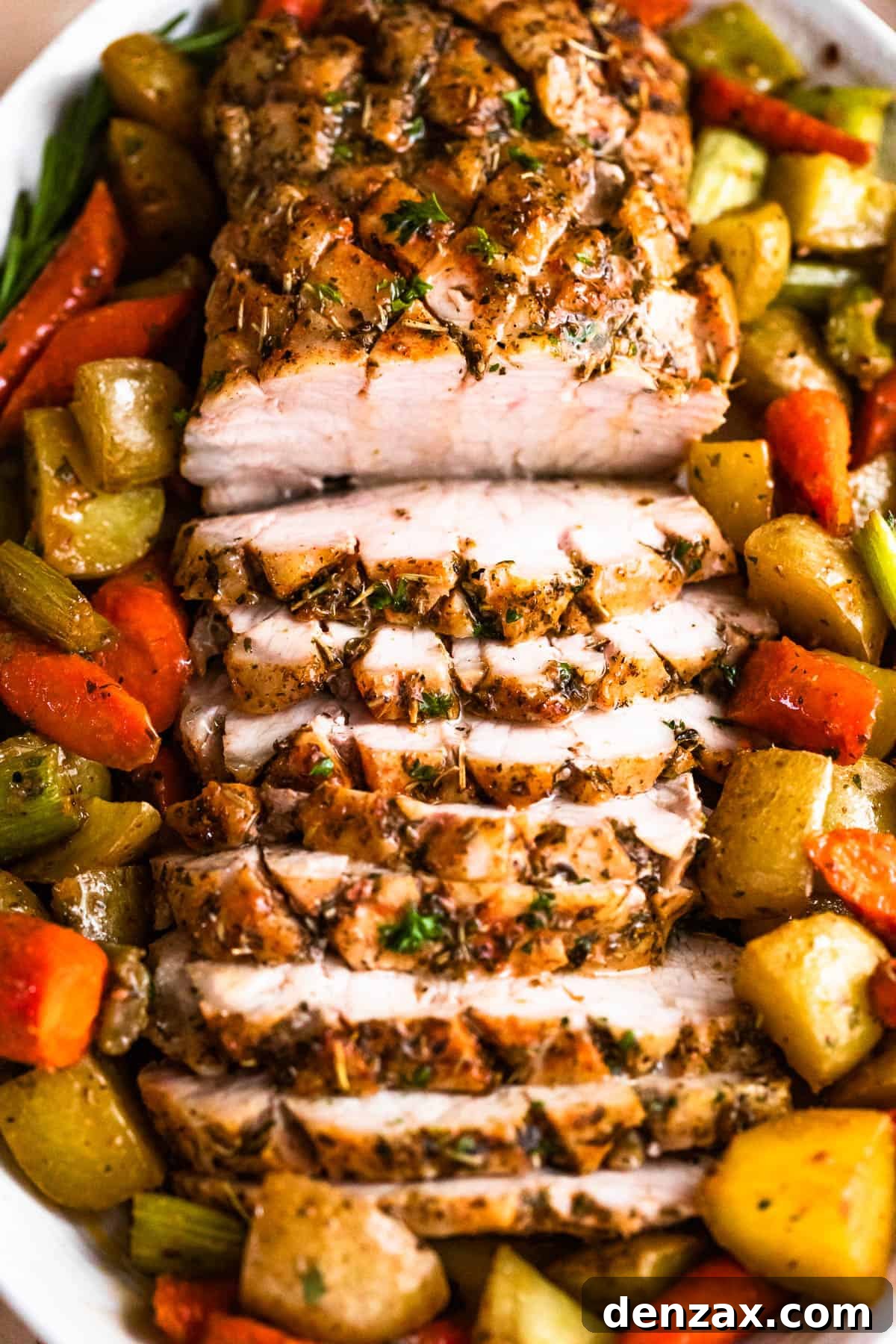 Herb-Crusted Pork Loin and Roasted Root Vegetables 8 overhead shot of oval plate with cooked and sliced pork loin roast and roasted vegetables arranged around the roast