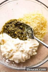 Mixing together basil pesto, mayonnaise, and parmesan cheese for the casserole sauce.