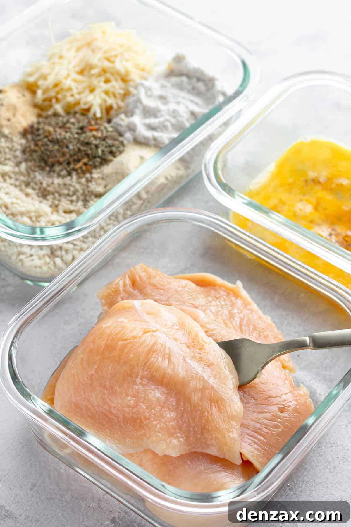 Three Glass Containers on a Counter – One Containing Raw Chicken, One Containing the Egg Mixture and One Containing the Un-Combined Breading Mixture