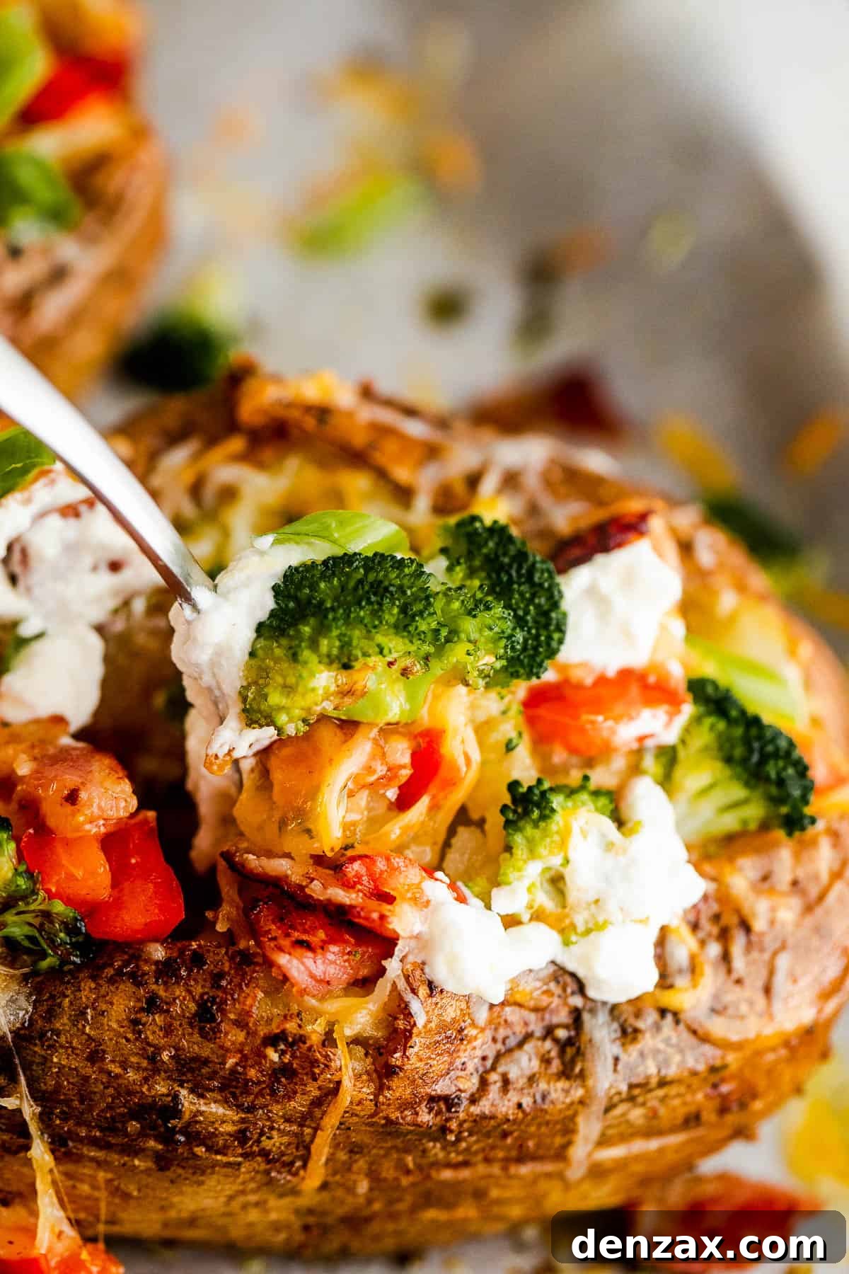 Digging into a loaded baked potato with a fork, showing fluffy interior