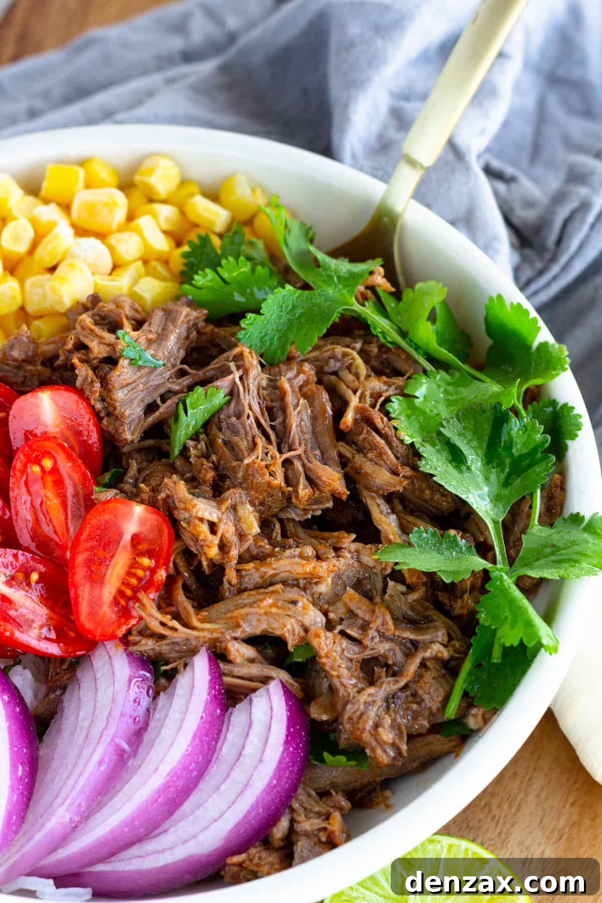 A vibrant beef barbacoa burrito bowl, topped with fresh parsley and featuring a golden spoon nestled inside, inviting a delicious first bite.