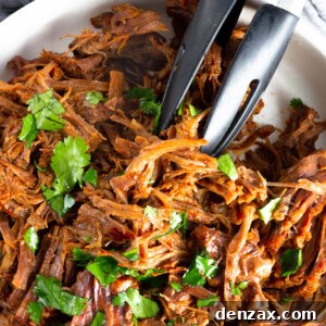 A White Bowl Containing Juicy Beef Barbacoa with Some Fresh Parsley on Top
