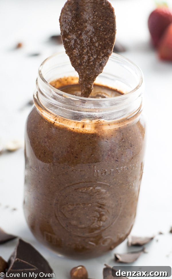 Freshly made Notella in a jar with spoon, surrounded by hazelnuts