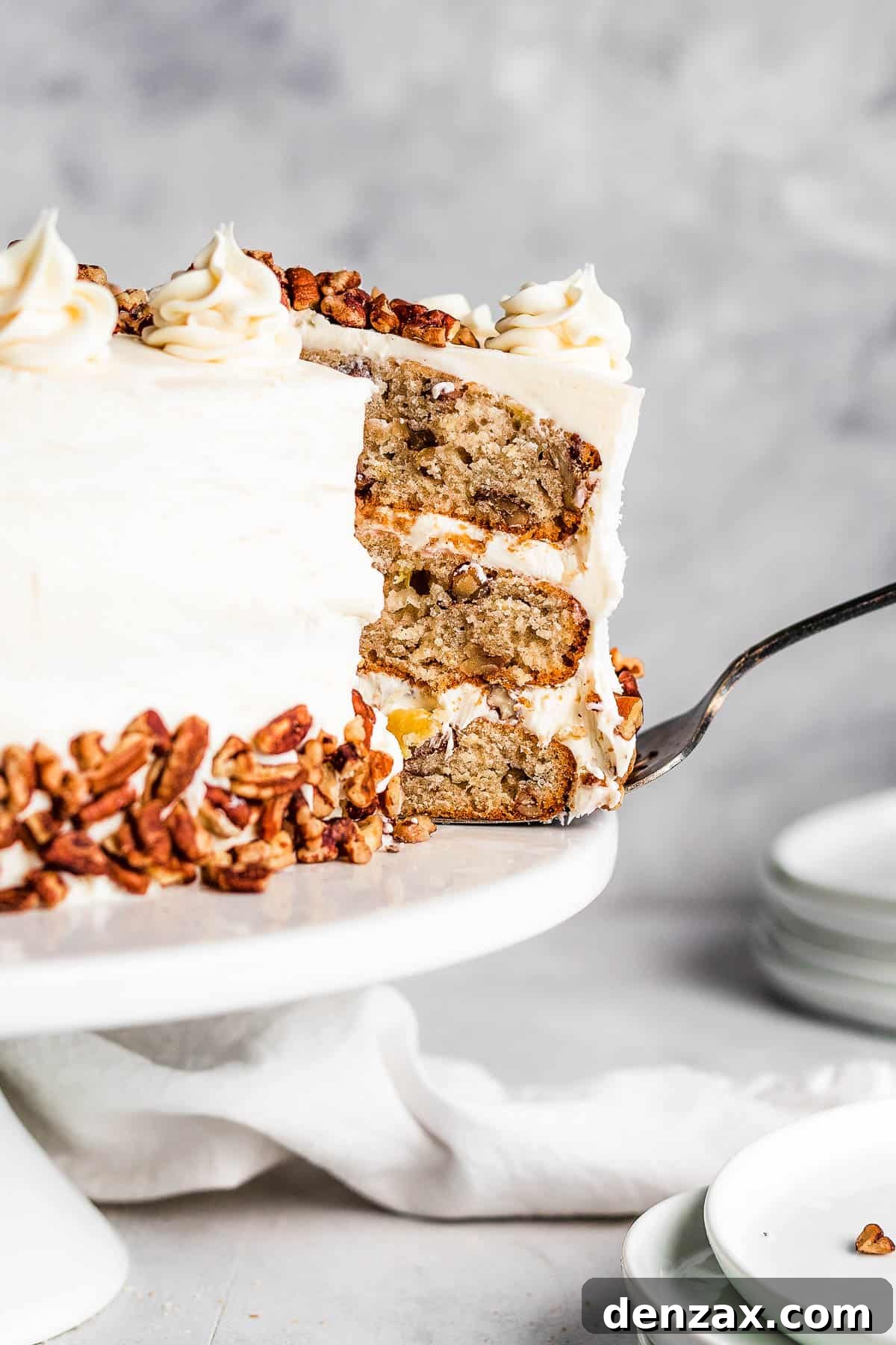 A Slice of Frosted Layer Cake Being Lifted From a Cake Stand