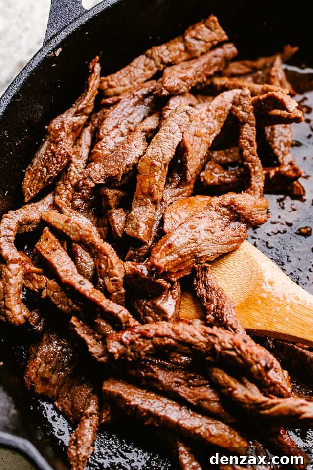 Searing thin strips of flank steak in a hot skillet, ready for the delicious soy sauce glaze.