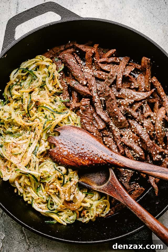 A vibrant skillet meal featuring flank steak and zucchini noodles, glistening with a savory soy sauce glaze.