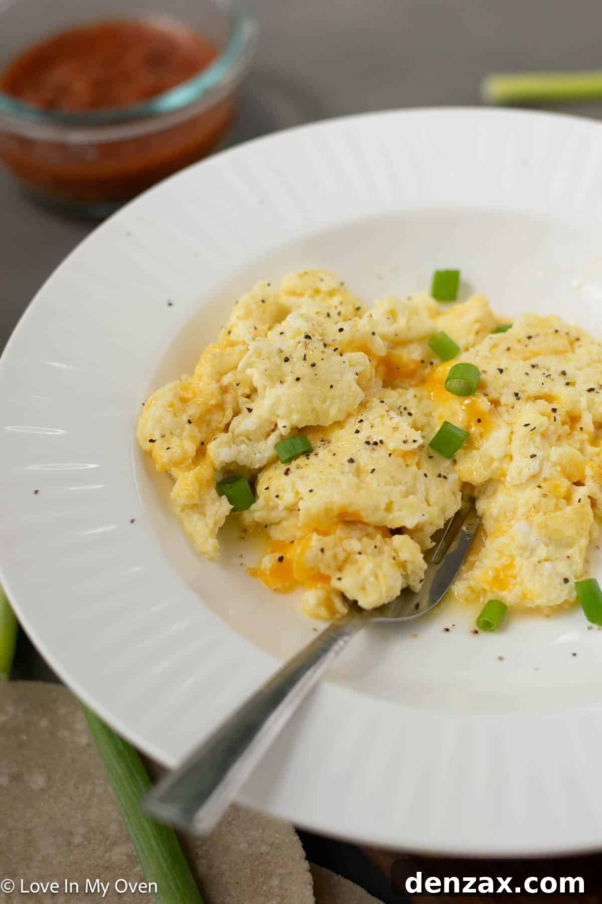 A close-up of high protein scrambled eggs with green onion and hot sauce