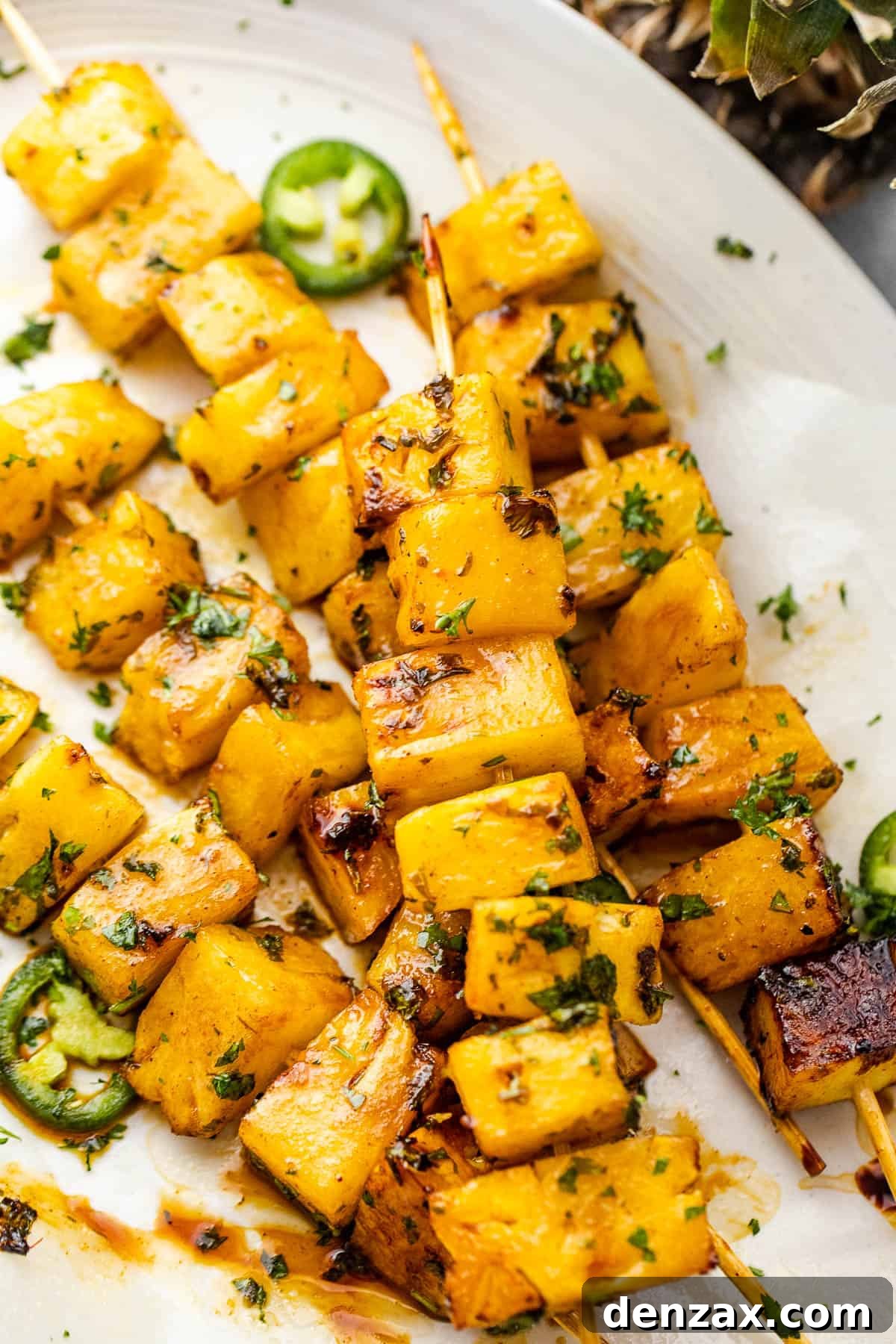 Tequila grilled pineapple skewers served on a rustic plate, garnished with fresh cilantro.