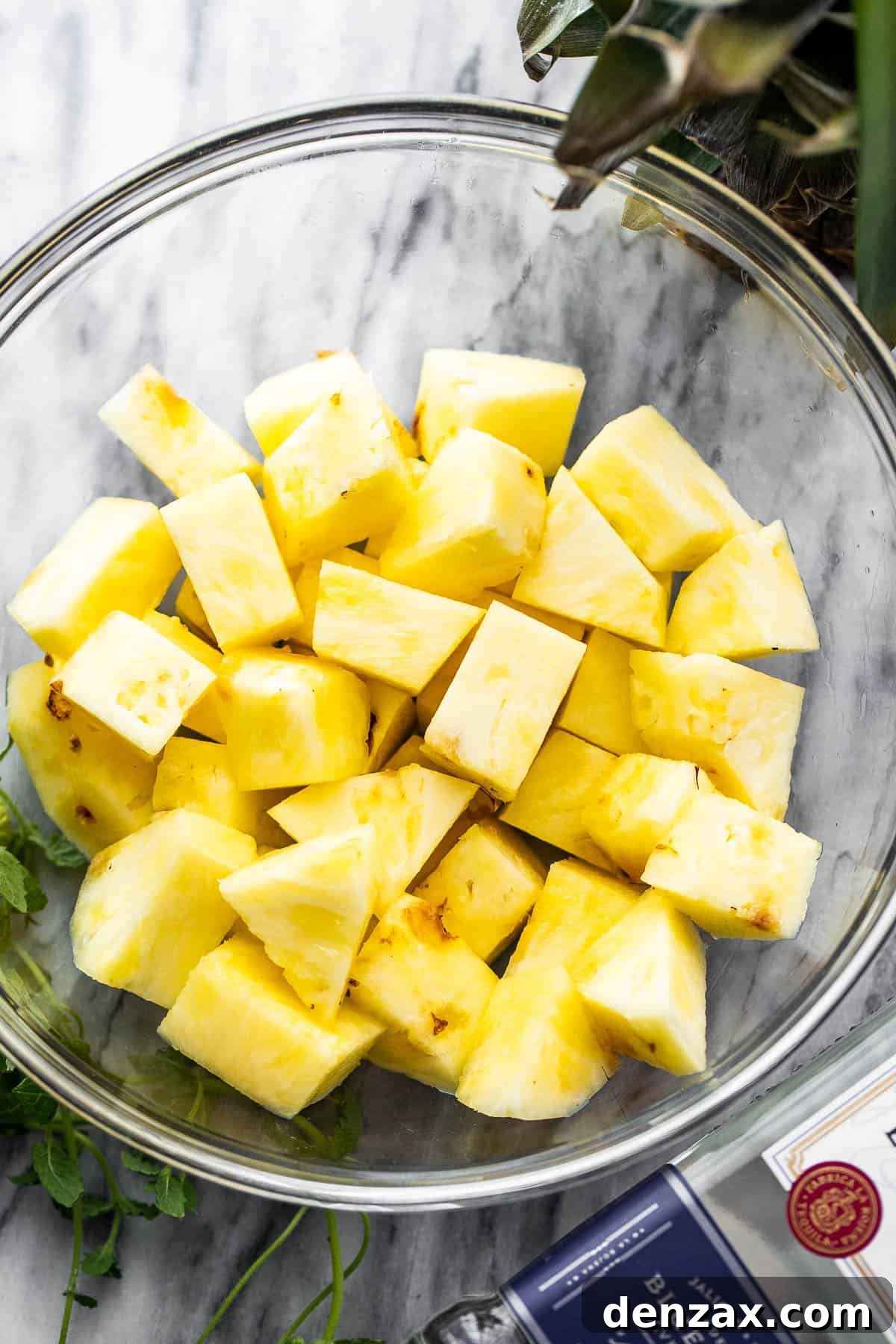 Diced fresh pineapple in a clear glass bowl, ready for preparation.