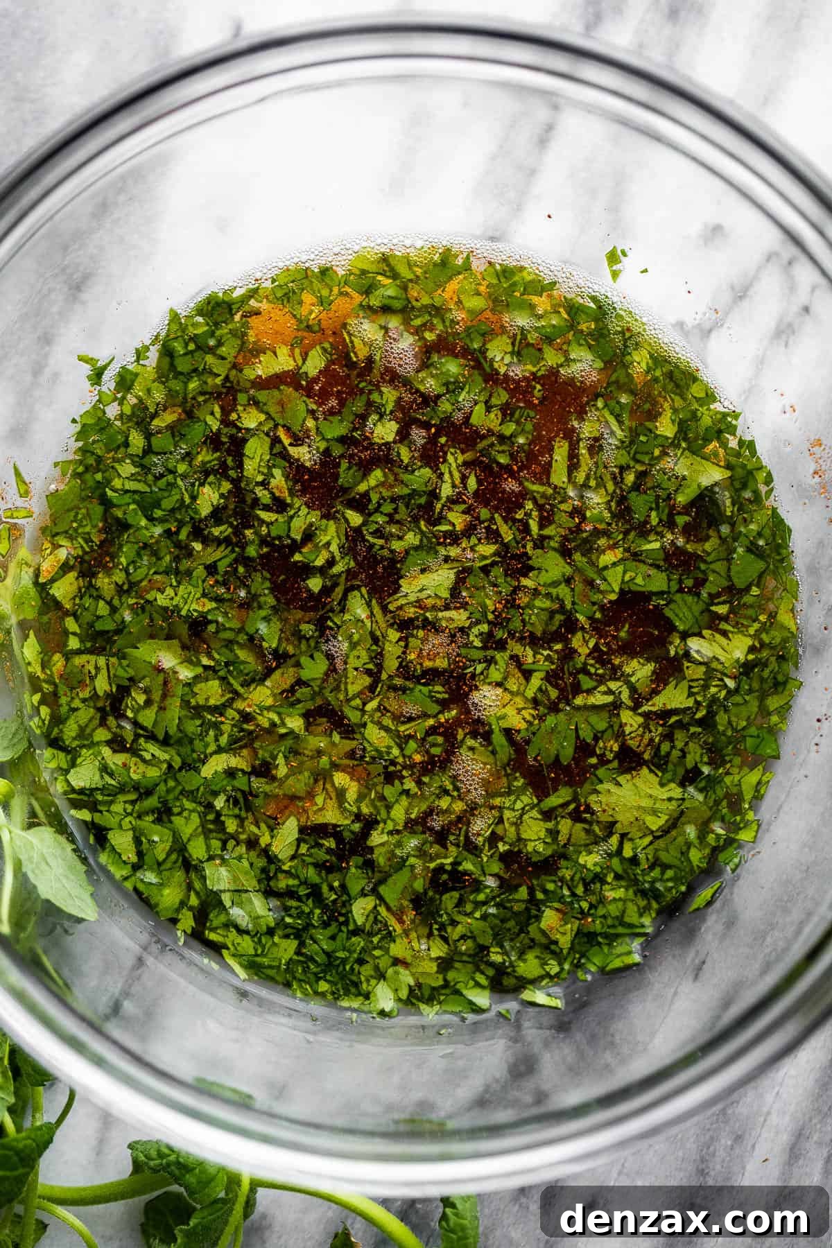 A mixing bowl containing tequila, fresh cilantro, and brown sugar, prepared for the marinade.