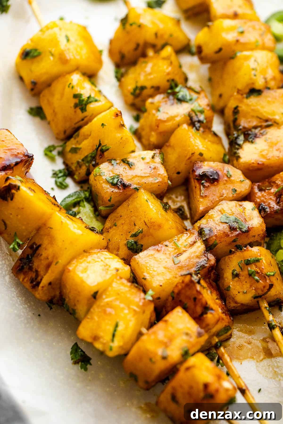 Side view of freshly grilled tequila pineapple skewers topped with finely chopped cilantro.