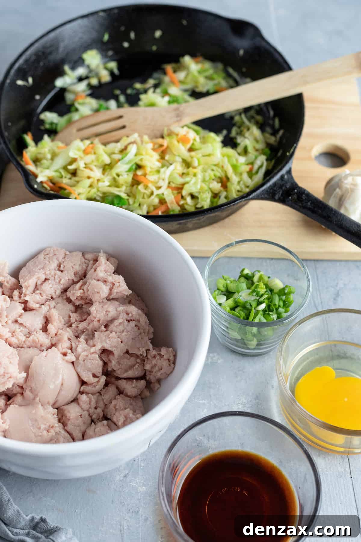 A bowl of ground chicken, a dish of soy sauce, and the rest of the filling ingredients on a table