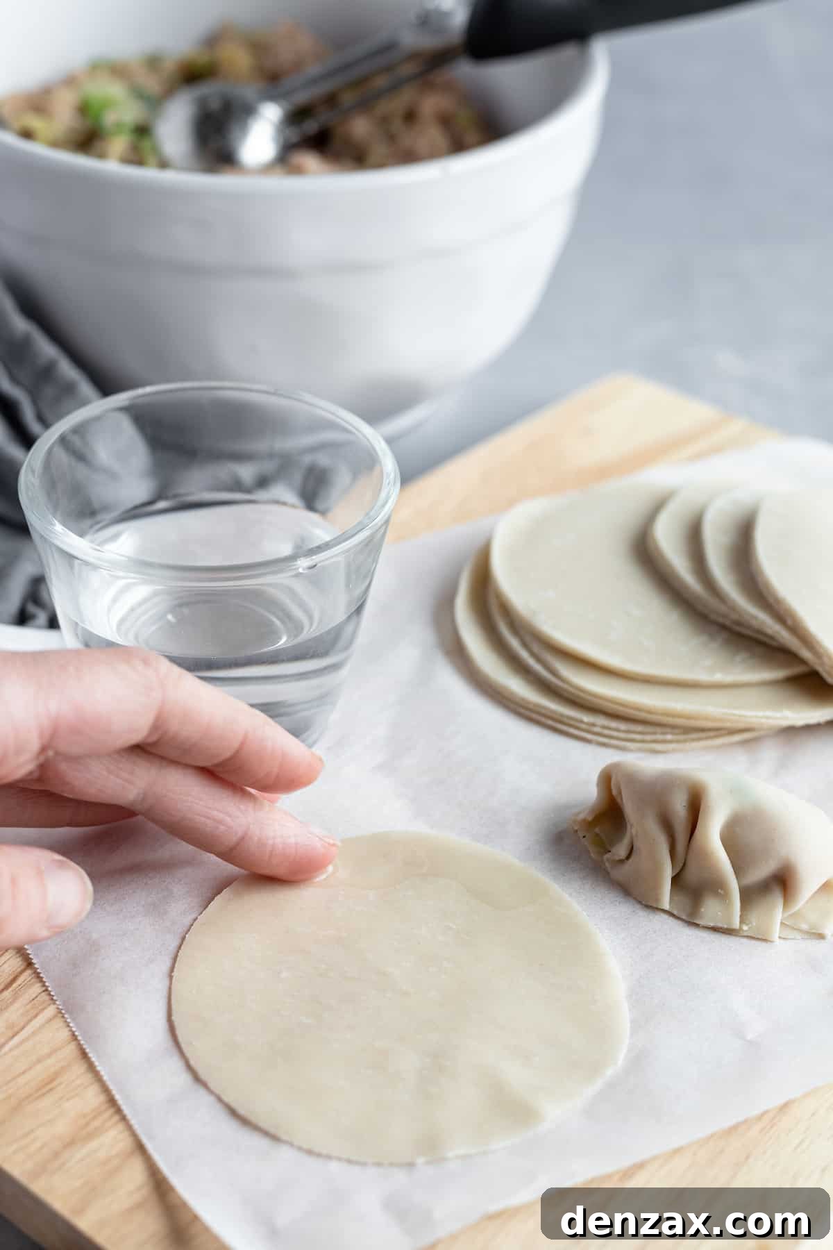 Water being rubbed on a round Asian dumpling wrapper
