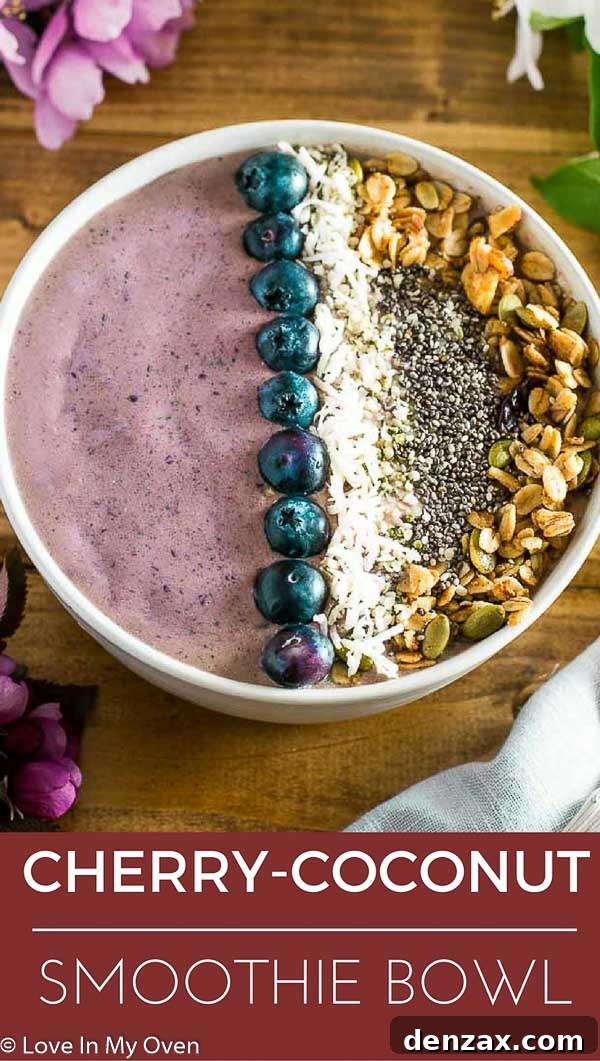 Close-up of a beautifully topped cherry coconut smoothie bowl with granola, fresh fruit, and coconut flakes