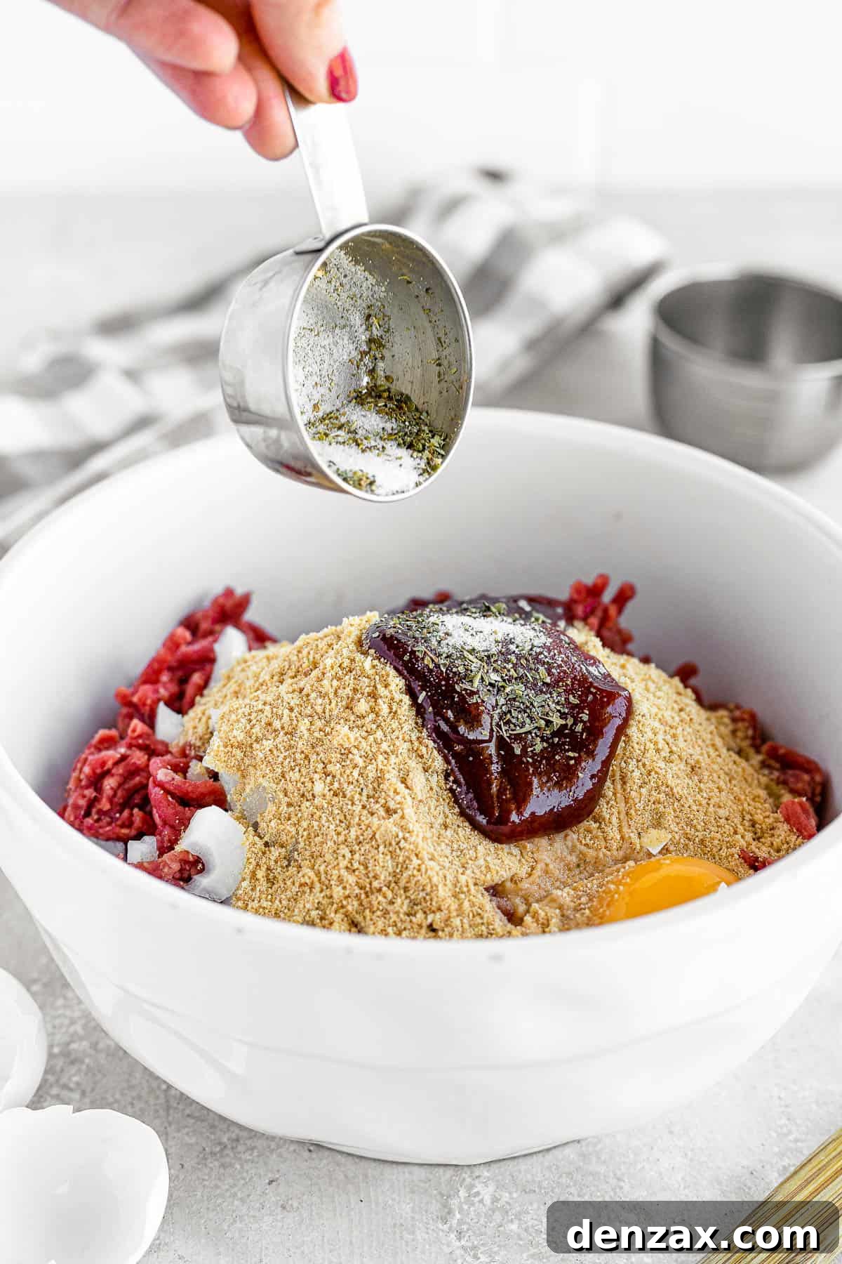 A large mixing bowl filled with the raw meatloaf mixture, positioned next to a foil-lined glass loaf pan on a gray countertop.