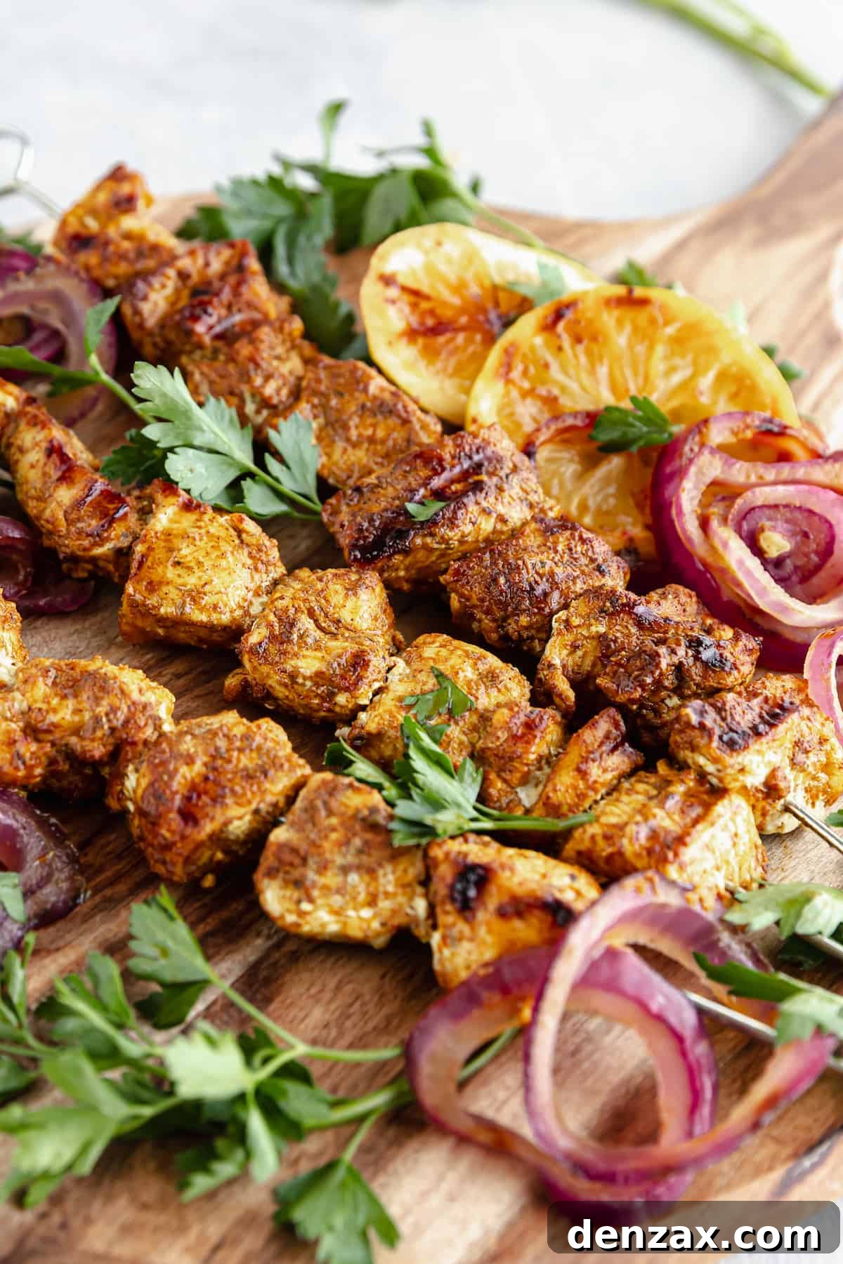 A Cutting Board on a Table Holding Onions, Lemon Slices and Shawarma Grilled Chicken Skewers