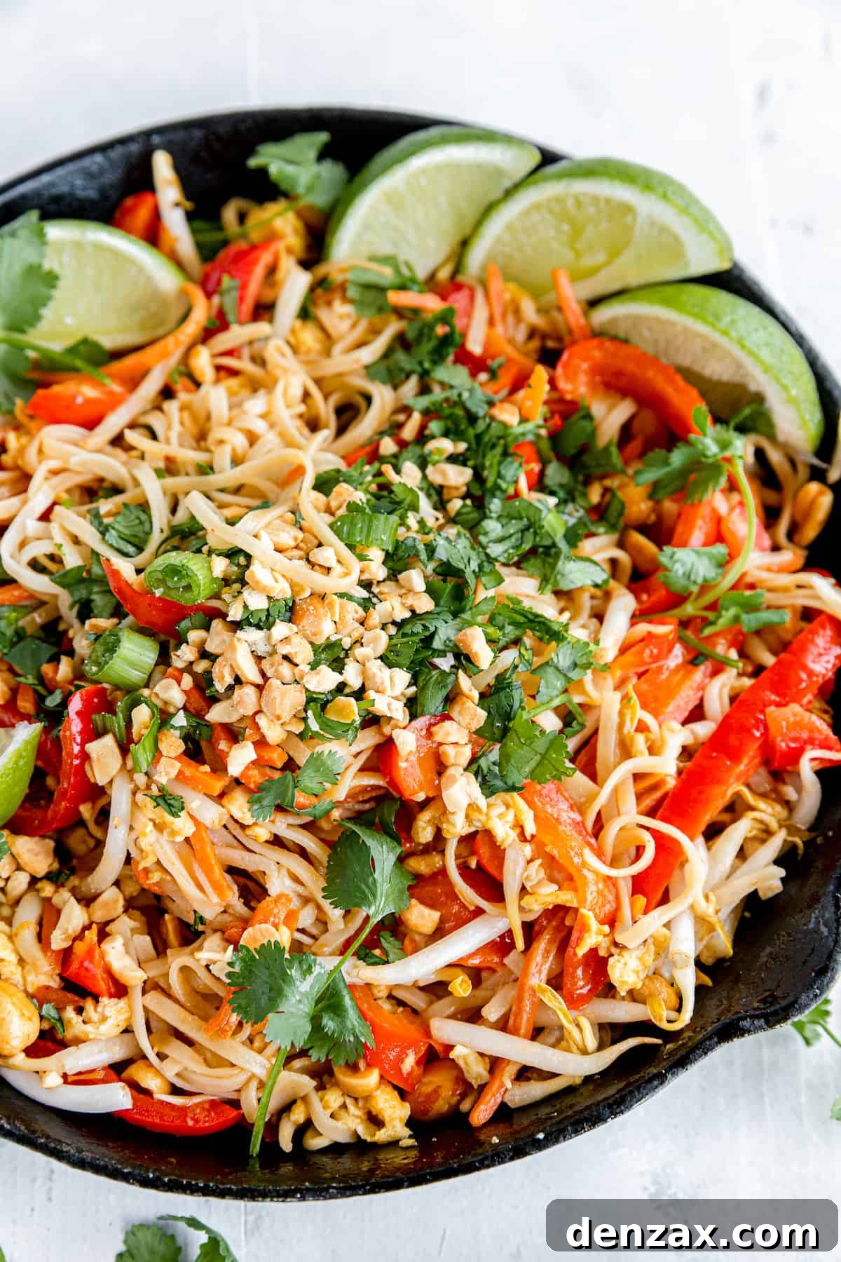 A Black Skillet Filled with Pad Thai on Top of a White Dinner Table