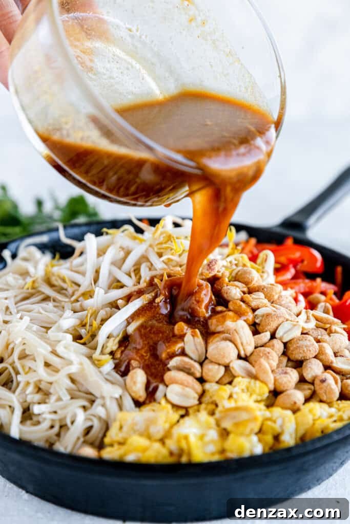 Pad Thai Sauce Being Poured Over the Skillet of Prepared Pad Thai