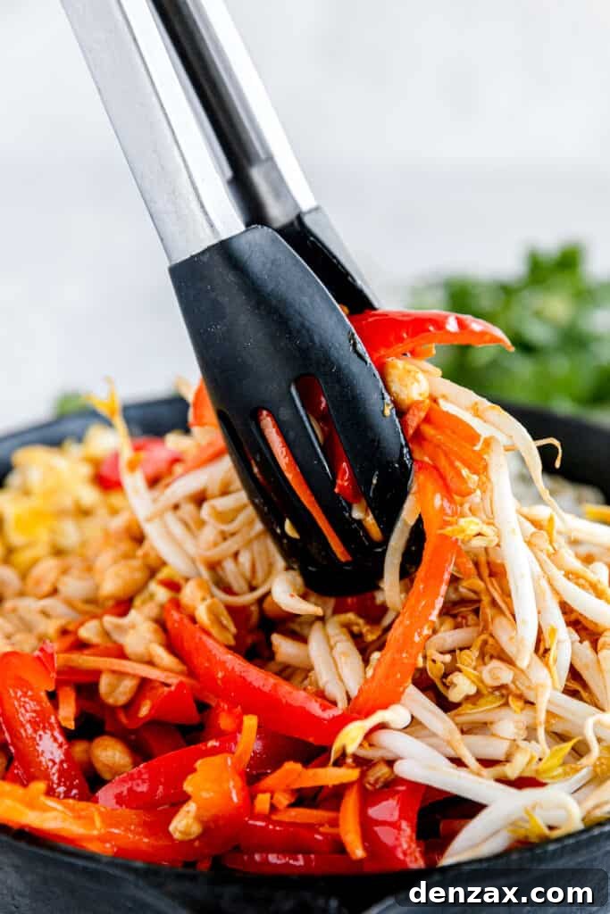 The Prepared Veggies and Nuts for Pad Thai Being Mixed with a Pair of Tongs