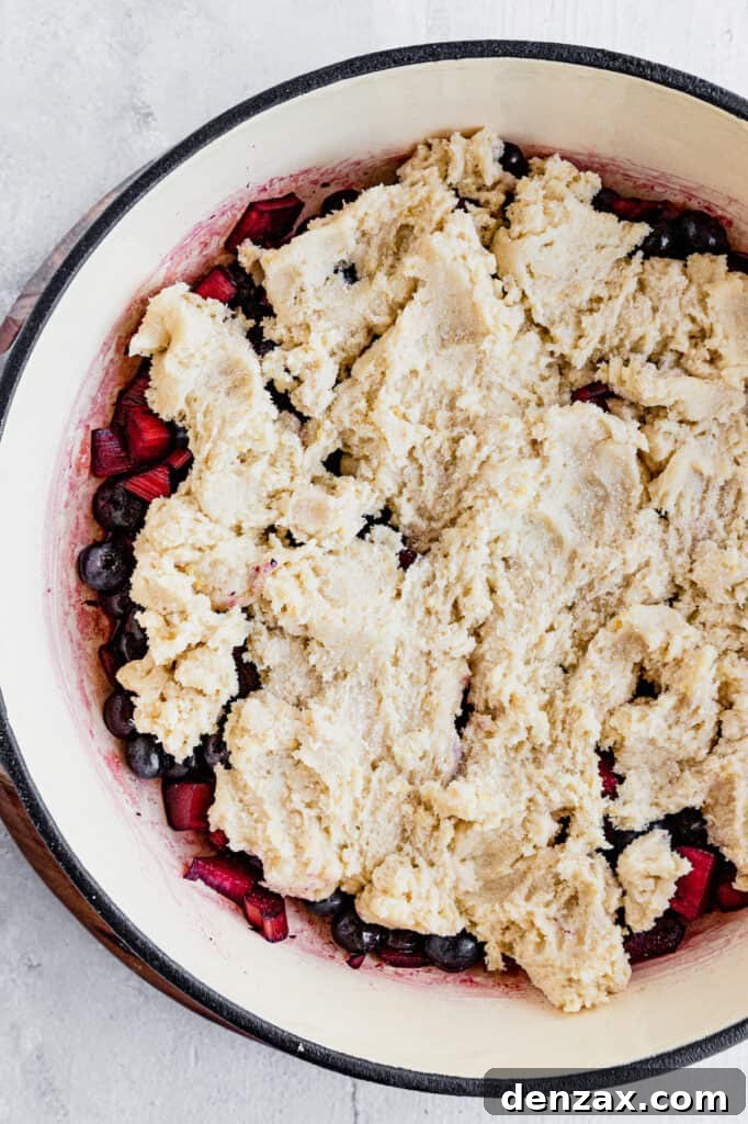 A pan filled with the blueberry rhubarb filling, evenly covered with the sandy-textured cobbler topping