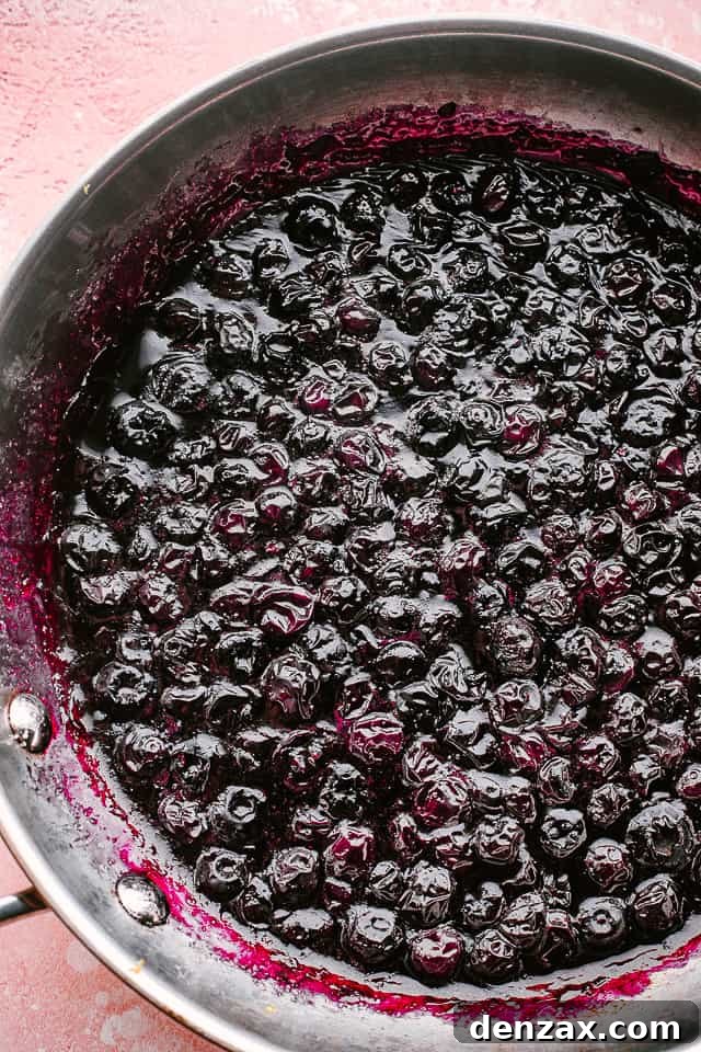 Blueberries cooking down in a pan, bubbling gently, as they transform into a rich sauce.