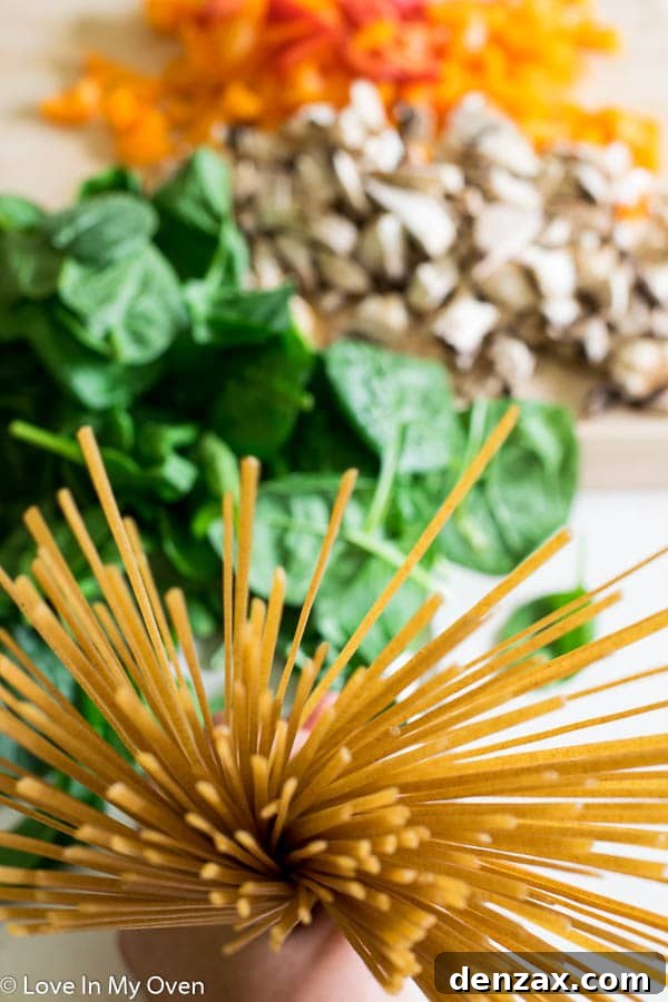 Close-up of creamy skillet linguine with ground beef and visible vegetables, garnished with fresh basil.