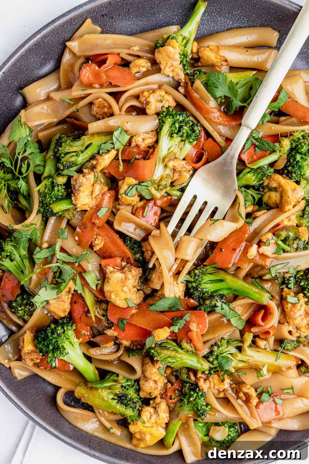 A Fork Digging Into a Big Plate of Pad See Ew