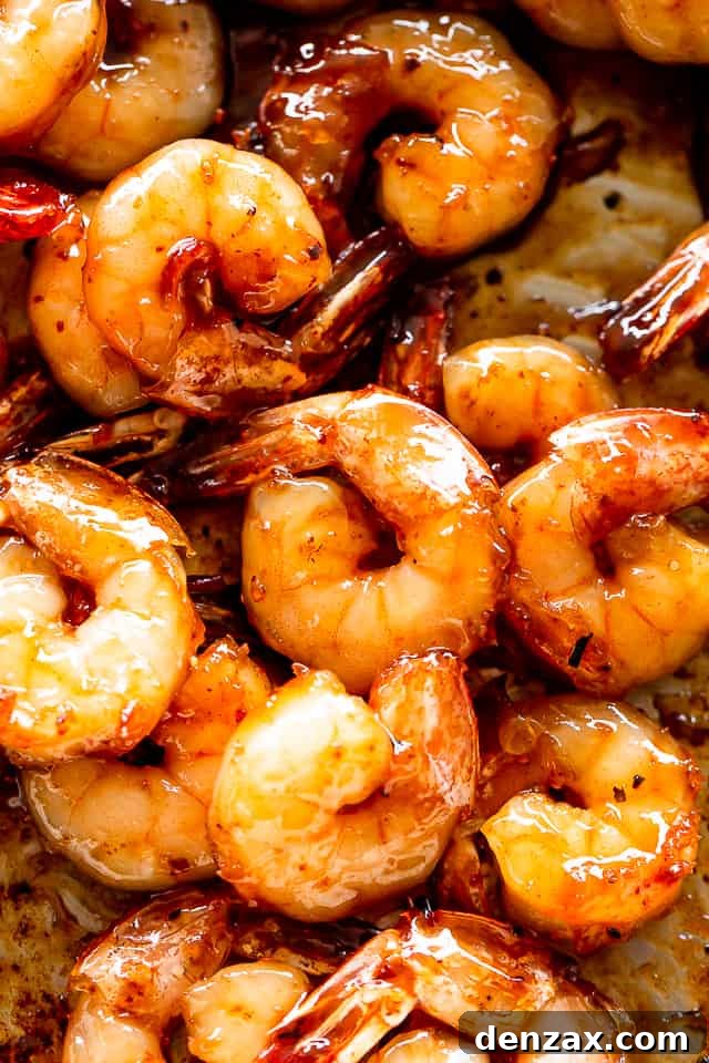 Honey garlic shrimp sizzling in a non-stick skillet, garnished with fresh parsley.