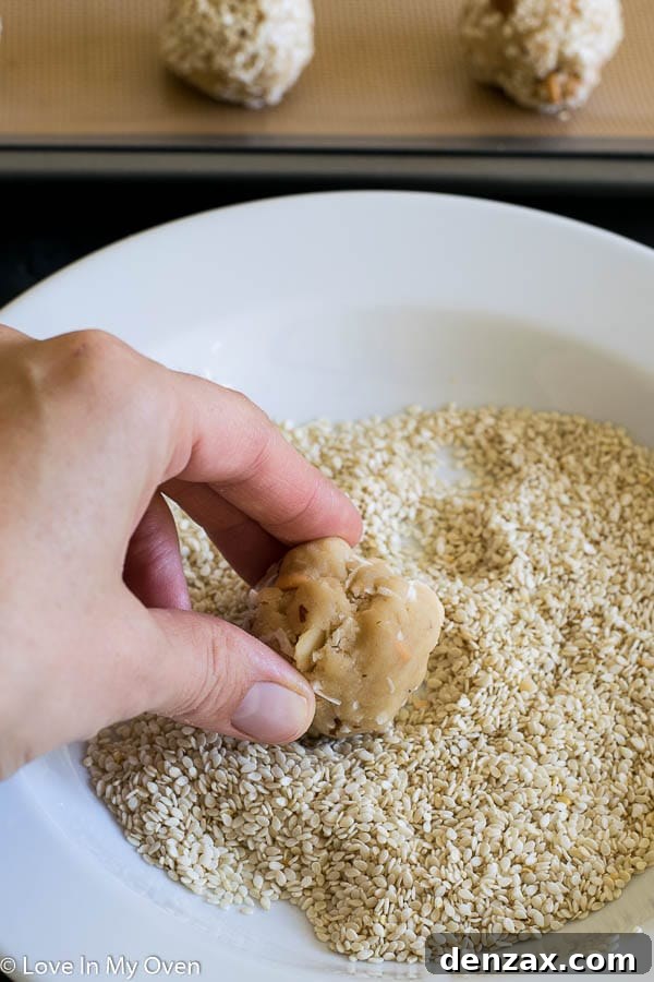 Unbaked Butterscotch Mountain Cookies rolled in sesame seeds on a baking sheet
