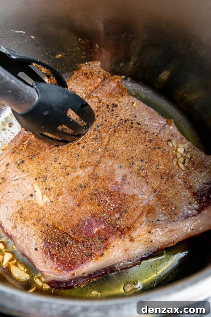 Browning steak with tongs in the Instant Pot.